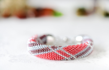 Bead crochet bracelet made of red and brown beads on a textile backgroundの写真素材