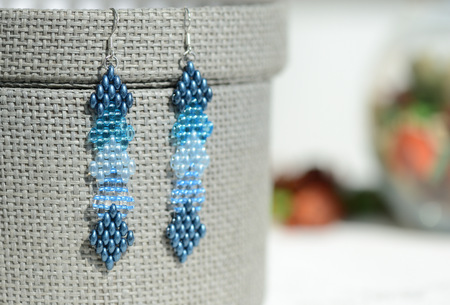 A pair of blue beaded earrings on a textile background close upの写真素材
