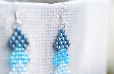 A pair of blue beaded earrings on a textile background close upの写真素材