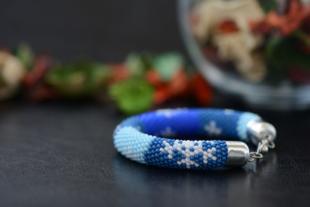Blue beaded bracelet with images of snowflakes on a dark backgroundの写真素材