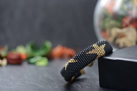 Black beaded bracelet with golden stars on a dark backgroundの写真素材