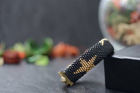 Black beaded bracelet with golden stars on a dark backgroundの写真素材
