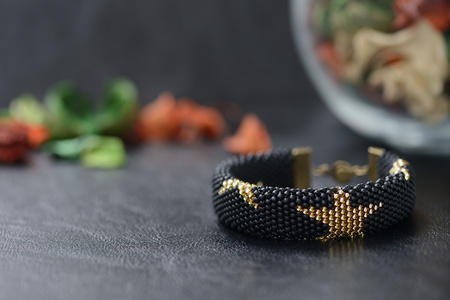 Black beaded bracelet with golden stars on a dark backgroundの写真素材