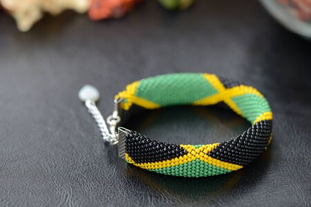 Bead crochet bracelet in the colors of the flag of Jamaica on a dark backgroundの写真素材