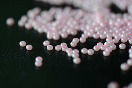 Pink seed beads on a dark background close up