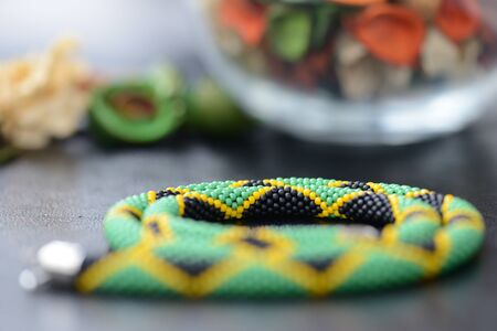 Necklace in colors of Jamaican flag on a dark background close upの写真素材
