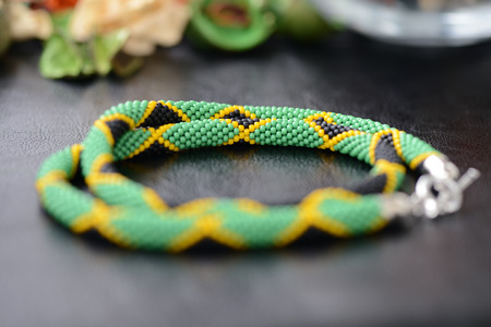 Necklace in colors of Jamaican flag on a dark background close upの写真素材