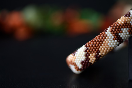 Camouflage bracelet made of seed beads on a dark background close upの写真素材