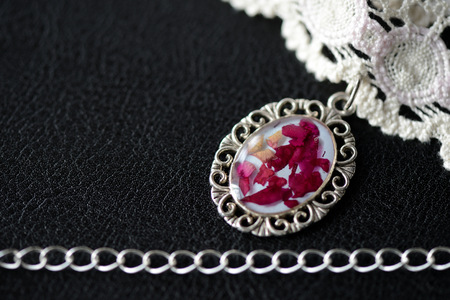 Beige lace choker with a rose petals pendant on a dark background