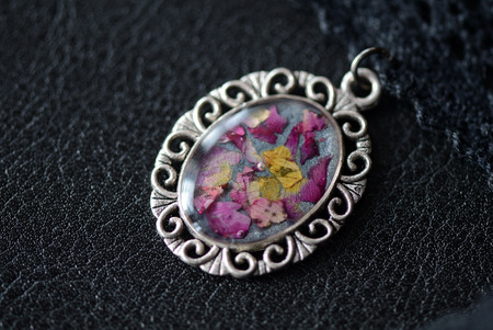 Black lace choker with a pendant made of epoxy resin and rose petalsの写真素材