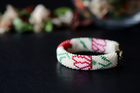 Beige beaded bracelet with flower print on a dark background close upの写真素材