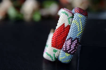 Beige and gray beaded bracelets with flower print on a dark background close upの写真素材