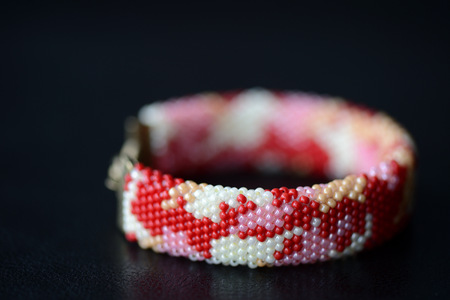 Red camouflage seed beads bracelet on a dark background close upの写真素材