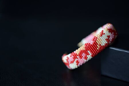 Red camouflage seed beads bracelet on a dark background close upの写真素材