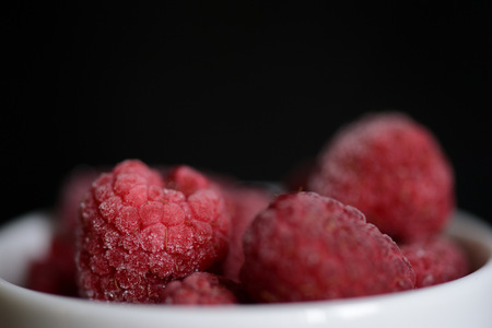 Frozen berries of raspberries on a dark background close upの写真素材