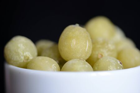 Frozen gooseberries on a dark background close up
