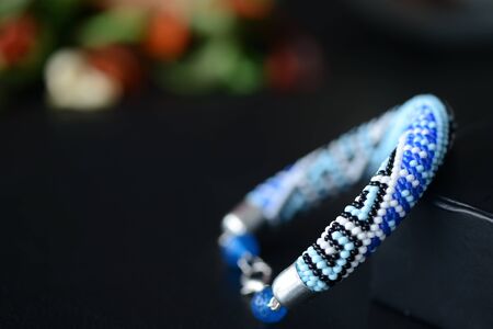 Blue beaded bracelet with greek ornament on a dark background close upの写真素材