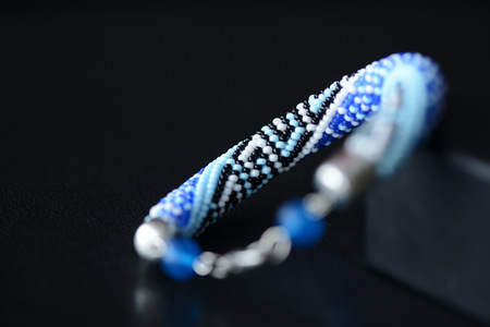 Blue beaded bracelet with greek ornament on a dark background close upの写真素材