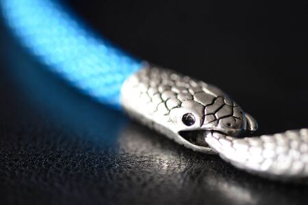 Blue beaded necklace with snake head lock on a dark background close upの写真素材