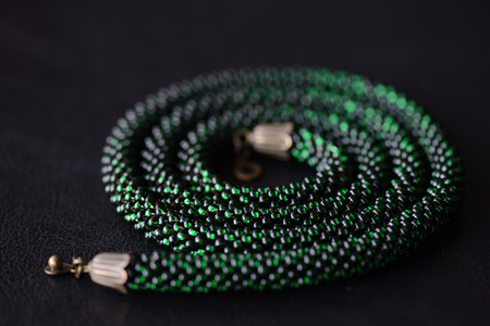 Bead crochet necklace green color on a dark background close up