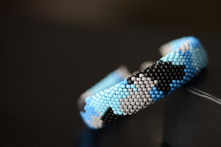 Blue beaded bracelet camouflage coloring on a dark background close upの写真素材