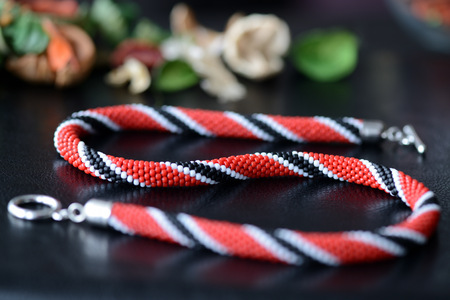 Bright beaded necklace red, black and white colors on a dark background close upの写真素材