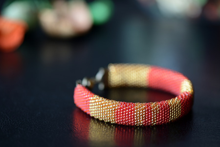 Red and yellow shiny bracelet made of small seed beads close up
