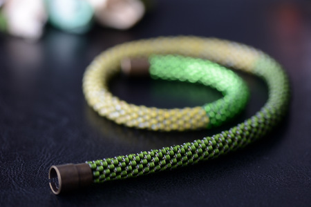Bead crochet necklace three shades of green on a dark background close upの写真素材