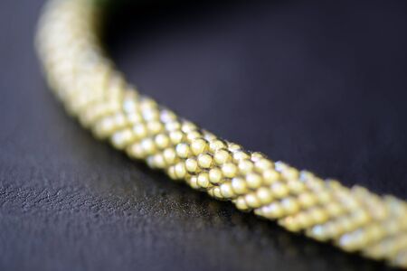 Fragment of a beaded necklace three shades of green on a dark background close upの写真素材