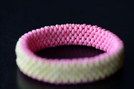 Green and pink bracelet made of twin beads on a dark background close upの写真素材