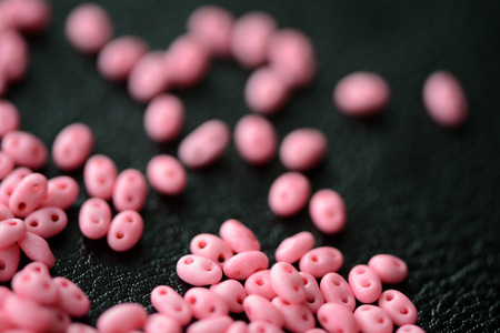 Scattered twin beads pink color on a dark surface close upの写真素材
