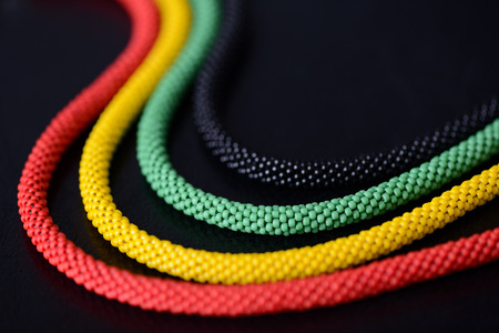 Fragment of a beaded necklace in Jamaican style on a dark background close up