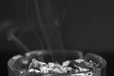 A piece of paper burning in a glass ashtray close up. Black and whiteの写真素材