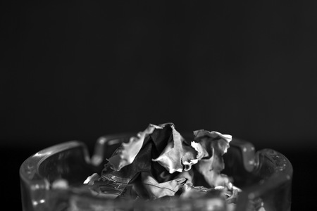 A piece of paper burning in a glass ashtray close up. Black and whiteの写真素材