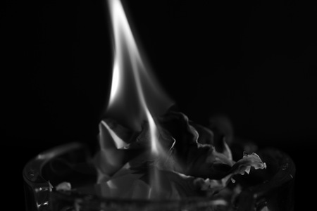 A piece of paper burning in a glass ashtray close up. Black and whiteの写真素材