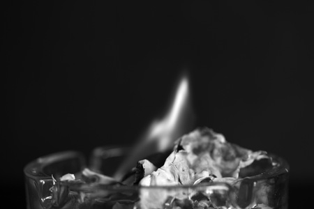 A piece of paper burning in a glass ashtray close up. Black and whiteの写真素材