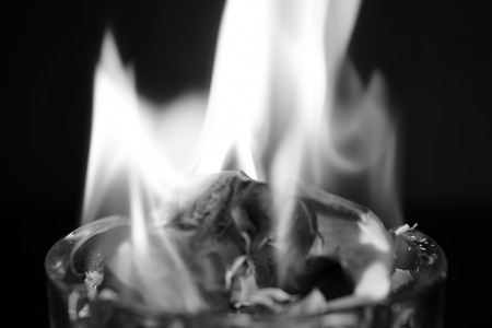 A piece of paper burning in a glass ashtray close up. Black and whiteの写真素材