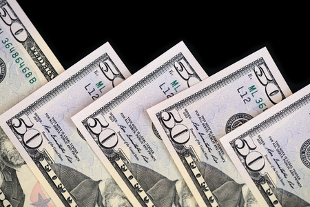 A pack of fifty dollar bills on a dark background