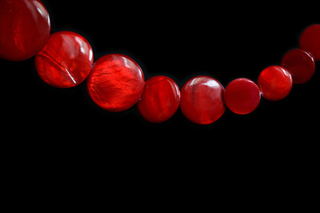 Red necklace from round flat beads on a dark background close up