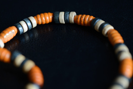 Fragment of a wooden necklace on a dark background close up