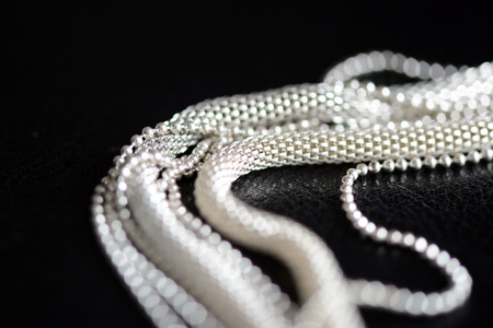 Metal necklace tied in a knot on a dark background close up