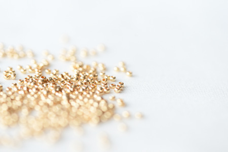 Golden seed beads scattered on textile background close upの写真素材