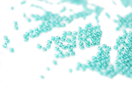 Seed beads of aquamarine color scattered on white surface close upの写真素材