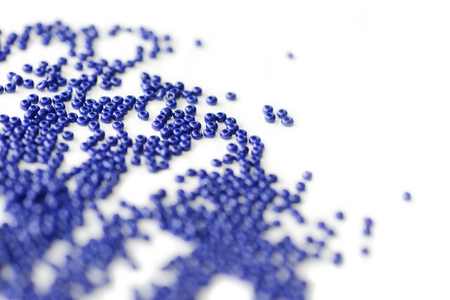 Dark blue seed beads scattered on a white surface close up