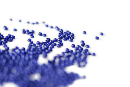 Dark blue seed beads scattered on a white surface close upの写真素材