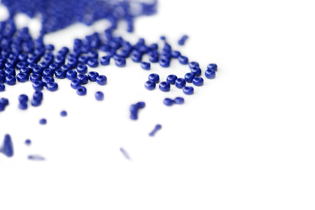 Dark blue seed beads scattered on a white surface close upの写真素材
