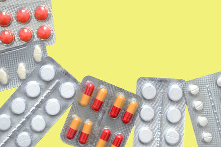 Packages of pills and tablets on a yellow background close up