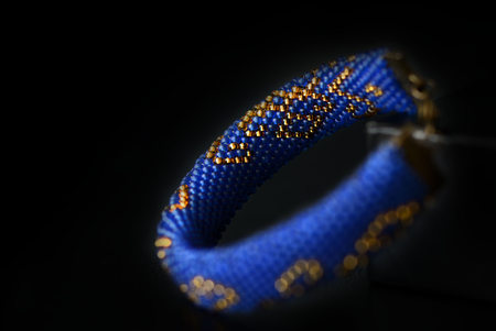 Blue bracelet with oriental print on a dark background close up