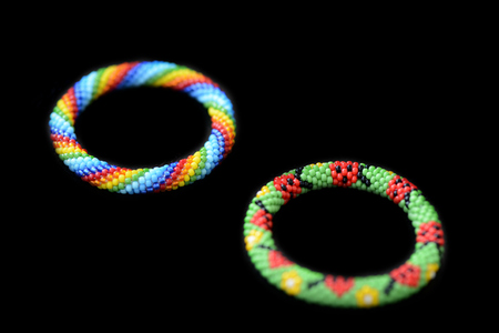 Two kid's summer bracelets made of seed beads isolated on a black background close up