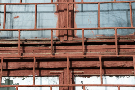 Old painted window behind rusty grate close up